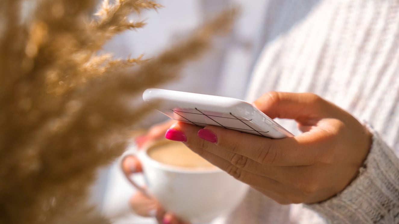 Woman Holding Mobile Phone. Pampas Grass Home Decoration. Checking Social Media While Drinking Cappuccino in the Breakfast Morning at Home. Aesthetics